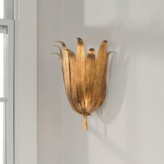 a gold metal flower on a white wall next to a window in a room with windowsills