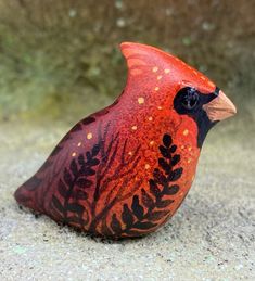 a red and black bird is sitting on the ground