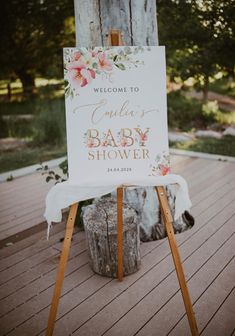 a baby shower sign sitting on top of a wooden easel