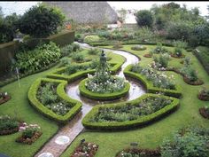 a garden with many different types of flowers and plants around it, including hedges in the shape of a heart