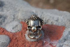 a silver skull ring sitting on top of a rock