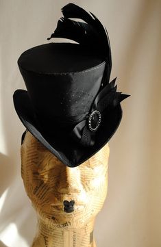 This gothic victorian mini top hat is an excellent choice for any dark cabaret event. It is covered with taffeta and embellished with various black trimmings. Two curled black rooster feathers, ribbons, a silver and black rhinestone round buckle and a just a hint of black veil. Choose between total black(pictured),blue or burgundy with black decoration. Measurements : height 4 inches( 10 cm ) front to back 9 inches ( 22 cm ) side to side 7.5 inches ( 19 cm ) This mini top hat is fully lined with Vintage Top Hat With Curved Brim For Costume Party, Carnival Adjustable Top Hat With High Crown, Vintage Curved Brim Top Hat For Costume Party, Adjustable High Crown Top Hat For Carnival, Gothic High Crown Costume Accessories For Costume Party, Gothic Black Brimmed Costume Hat, Black Gothic Mini Hats For Costume Party, Punk Top Hat For Halloween Party, Gothic High Crown Costume Accessories For Party