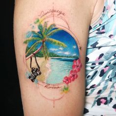 a woman with a camera and palm tree tattoo on her left arm, next to the ocean