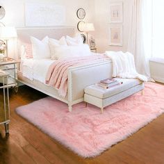 a white bedroom with pink rugs on the floor