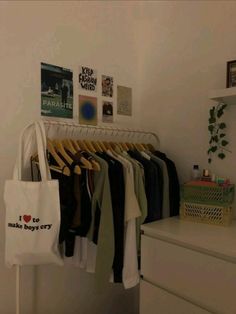 a white bag hanging on a rack with clothes and other items in the room next to it