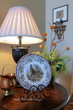 a table with a lamp, plate and flowers on it