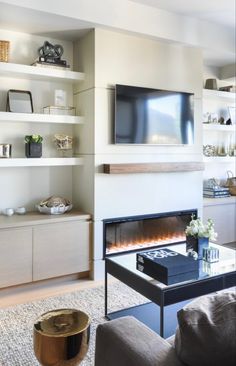 a living room filled with furniture and a flat screen tv mounted on the wall above a fire place