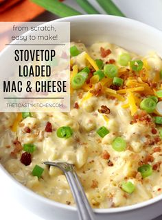 a white bowl filled with macaroni and cheese topped with green onions, cheddar