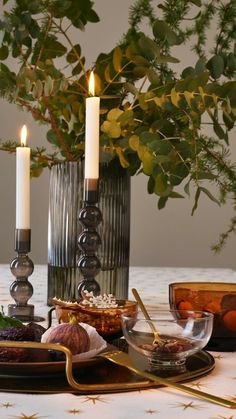 a table topped with plates and candles next to a potted plant