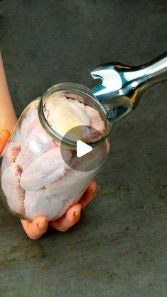 a person holding a jar filled with food and a pair of tongs in it