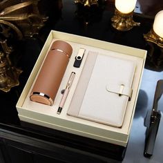 an open box with a pen, notebook and other items inside it on a table