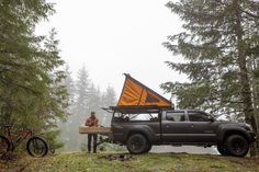 a man sitting at a table in the back of a truck with an awning on it