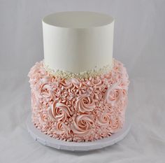 a white and pink wedding cake with flowers on the bottom layer, sitting on top of a plate