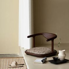 a wooden chair sitting on top of a floor next to a vase