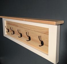 a coat rack with five hooks on it and two coats hanging from the top shelf