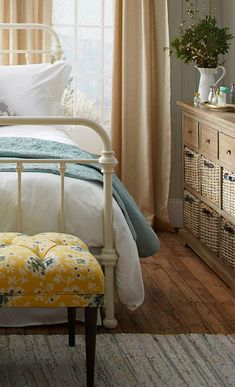 a white bed sitting next to a window in a room with wooden floors and curtains