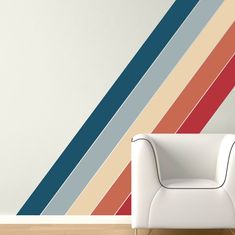 a white chair sitting in front of a wall with multicolored stripes on it