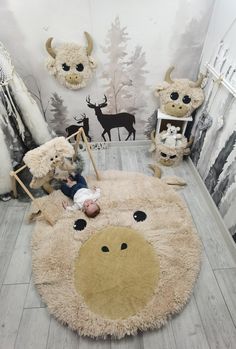 a baby laying on top of a rug in a room with deer head wallpaper