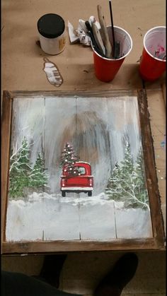 a red truck with a christmas tree on it is sitting in front of a painting