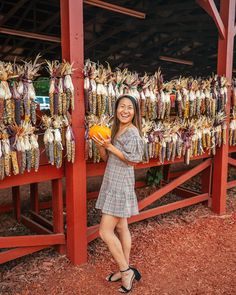 a woman standing in front of an open air market with corn on the cob