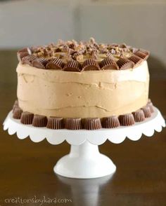 a cake sitting on top of a white cake plate covered in frosting and chocolate chips