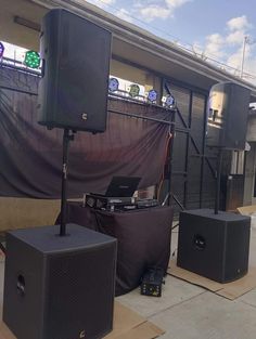 two speakers and a laptop are on the ground in front of a building with an awning