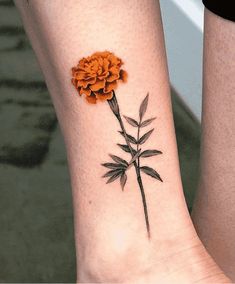 two people with tattoos on their legs and one has an orange flower in the middle