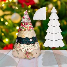 a paper christmas tree sitting on top of a table next to a cut out ornament