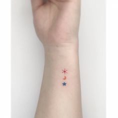 a person's arm with a small star and moon tattoo on the left wrist