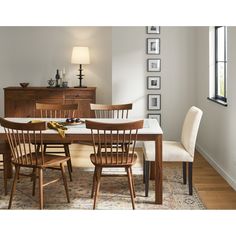 a dining room table and chairs in front of a window with pictures on the wall