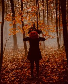 a woman standing in the middle of a forest with her hands on her head while wearing a pumpkin costume