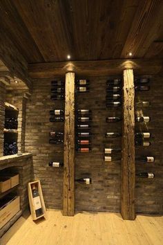 a wine cellar with several bottles on the wall and wooden pillars in front of it