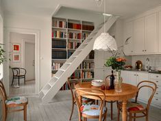 a dining room table with chairs and bookshelf in the background