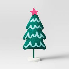 a green felt christmas tree on a white stand with a pink star on the top