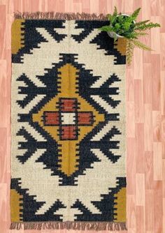 a black, yellow and white rug with a plant on it next to a wooden floor