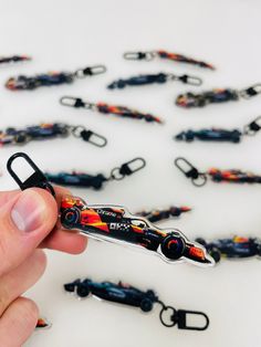 a hand holding a black and red object in front of a bunch of key chains