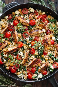 a skillet filled with chicken, tomatoes and chickpeas