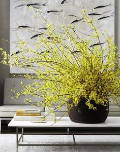 a vase filled with yellow flowers sitting on top of a table next to a painting