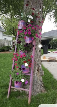 an old ladder is decorated with flowers and other things to decorate on the side of a tree