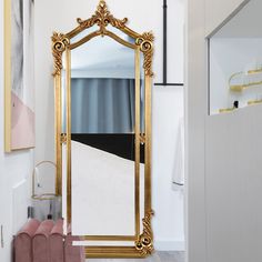 a large gold framed mirror sitting on top of a white floor