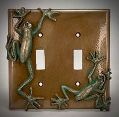 two frogs are sitting on the light switch cover