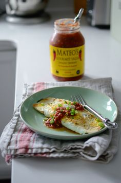 an omelet on a plate next to a jar of mustard and a fork