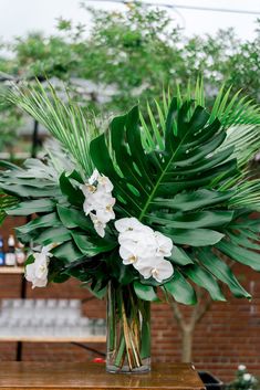 a vase filled with white flowers sitting on top of a wooden table next to a tree