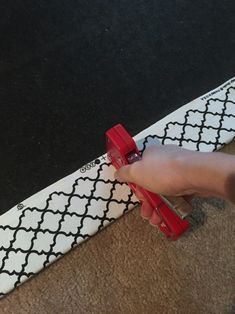 a person is holding a pair of red scissors over a black and white pattern on a surfboard