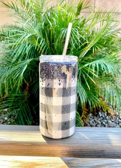 a cup with a straw in it sitting on a wooden table next to some plants