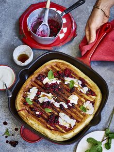 a pancake with berries and cream in it on a table next to other dishes