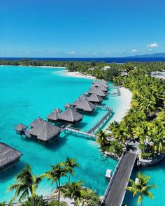 an aerial view of the water and beach in front of some huts with thatched roofs