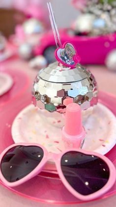 a pink table topped with sunglasses and a disco ball