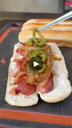 a hot dog on a bun with onions and peppers