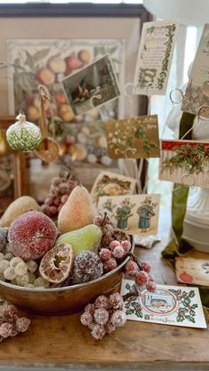 a bowl filled with fruit sitting on top of a table next to cards and decorations